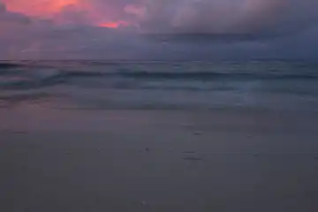 Abendstimmung am Meer, Sandstrand im Vordergrund, Wellen und Wolkenstimmung. Selayar, Südsulawesi, Indonesien