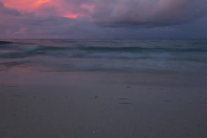 Abendstimmung am Meer, Sandstrand im Vordergrund, Wellen und Wolkenstimmung. Selayar, Südsulawesi, Indonesien