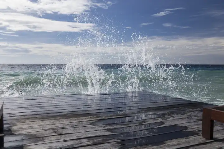 splashing waves wash over wooden jetty