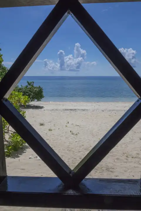 view through wooden balustrade on sandy coral beach, sea, blue sky and white cumulus