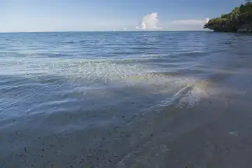 sanfter Wellensaum umspült im weichen Nachmittagslicht den Sandstrand von Selayar