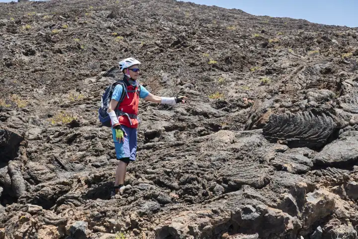 Mountainbikerin zeigt auf eine spezielle Formation von Stricklava auf El Hierro, Kanarische Inseln, Spanien
