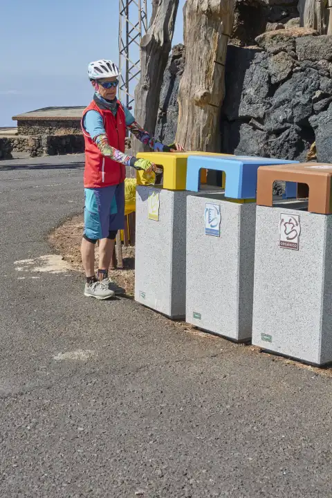 Mountain biker disposes of waste in appropriate garbage can. Avoid waste through recycling and waste separation. El Hierro, Canary Islands, Spain