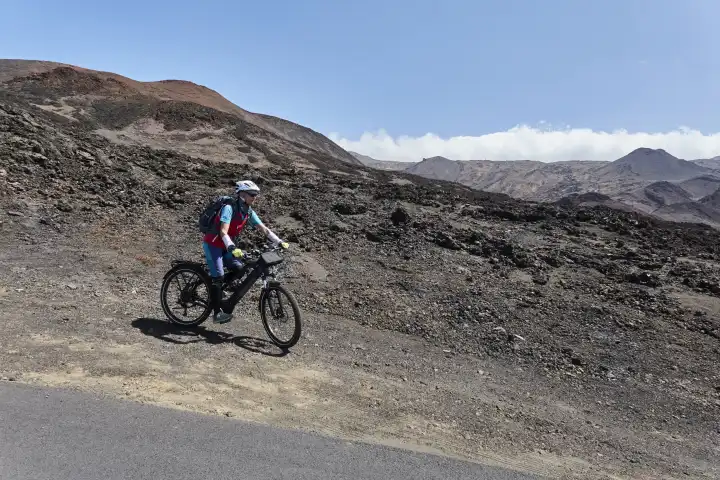 Mountain biker on the road in barren, volcanic landscape. El Hierro, Canary Islands, spain