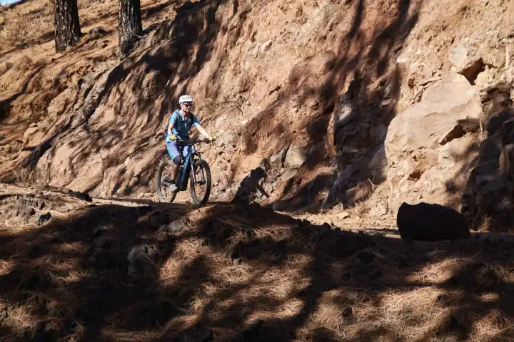 Mountain biker trails on trail past eroding steep slopes. La Palma, Canary Islands, Spain