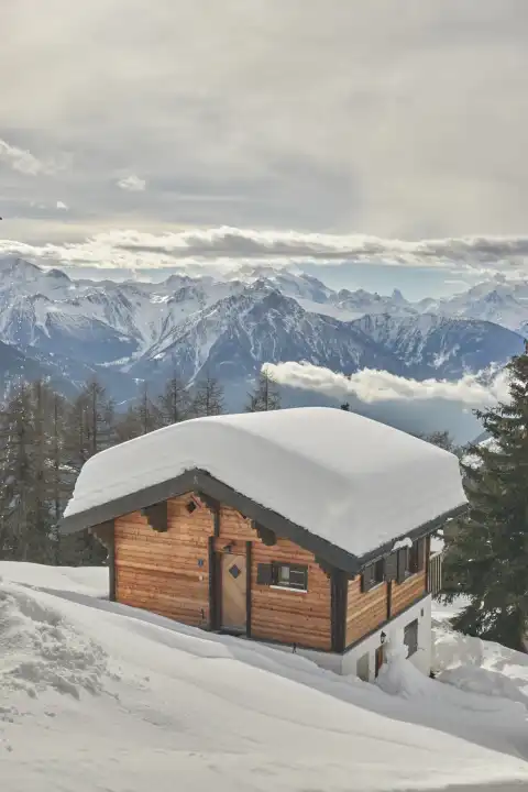 Light brown chalet with a view of the Valais mountains and an interesting cloudy atmosphere. Valais, Switzerland