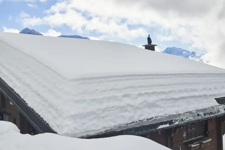 Gut erkennbarer Schneedeckenaufbau auf dem Satteldach eines Chalets. Wallis, Schweiz