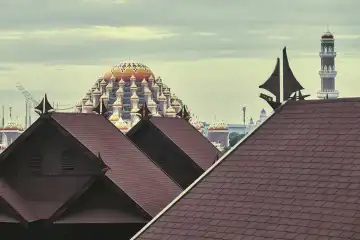 View over saddle roofs decorated with a traditional sailing boat as a gable. behind 99 domed mosque, Makassar, Sulawesi, Indonesia