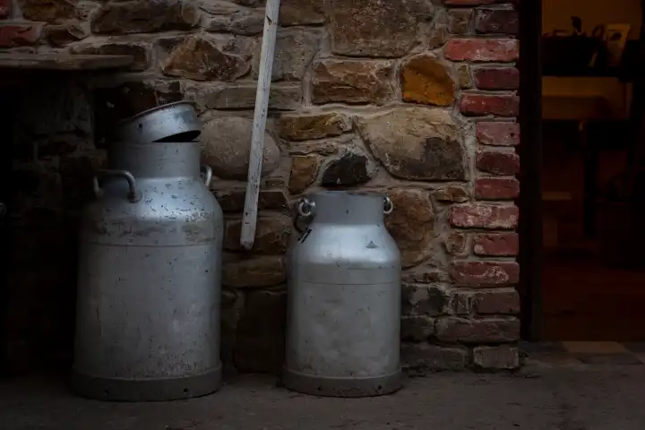 Milk cans in front of a natural stone wall