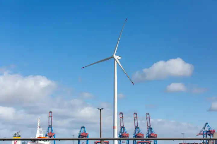 Wind turbine in front of the port of Hamburg with cranes