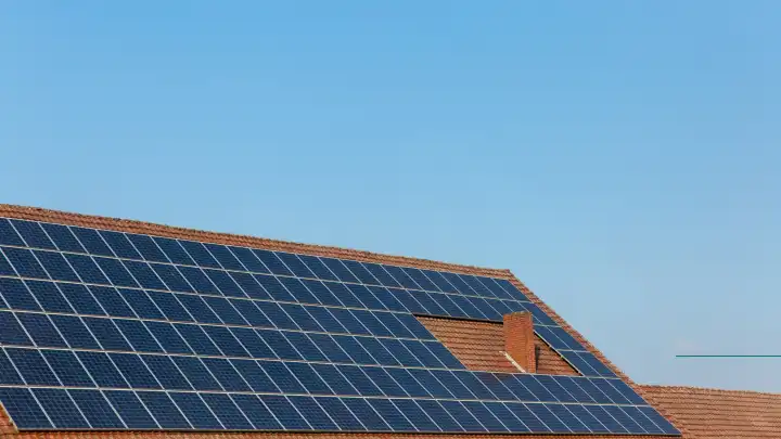 Photovoltaic system on a roof in front of a blue sky