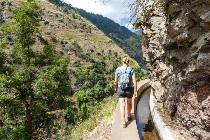 Madeira, Portugal - September 14, 2022: Young woman hiking along the Levada Nova hiking trail on Madeira Island, Portugal.