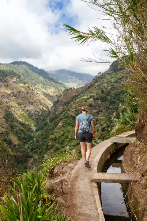 Madeira, Portugal - September 14, 2022: Young woman hiking along Levada Nova hiking portrait hiking trail on Madeira Island, Portugal.