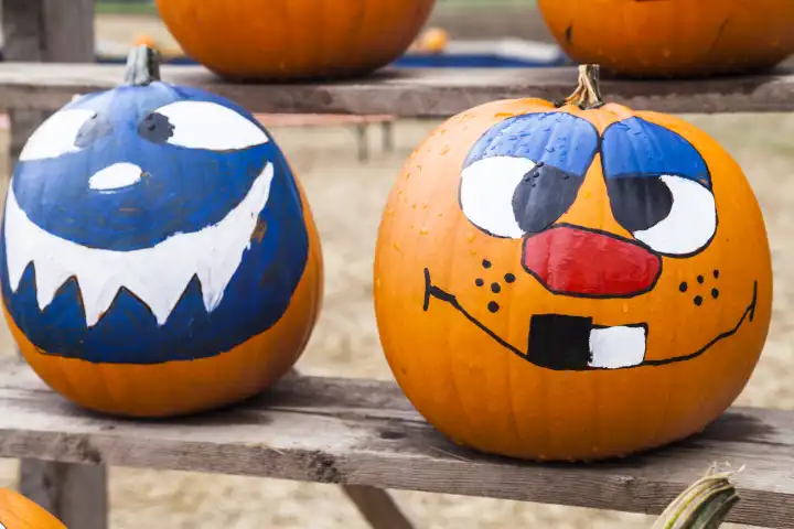 Two pumpkins with faces painted on them