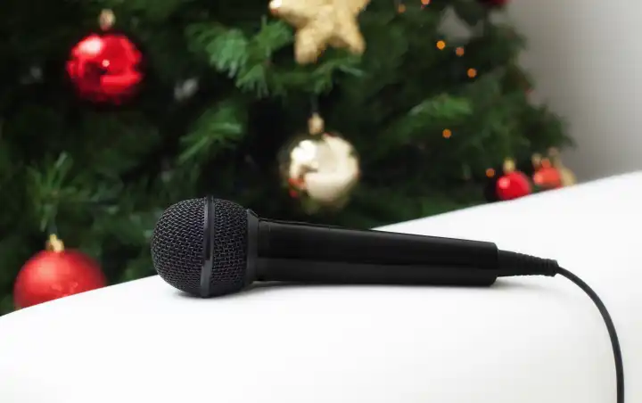 Black microphone on white leather sofa near the Christmas tree Concept of Christmas sung music