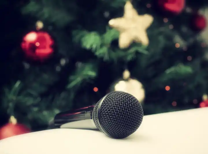 Black microphone on white leather sofa near the Christmas tree Concept of Christmas sung music