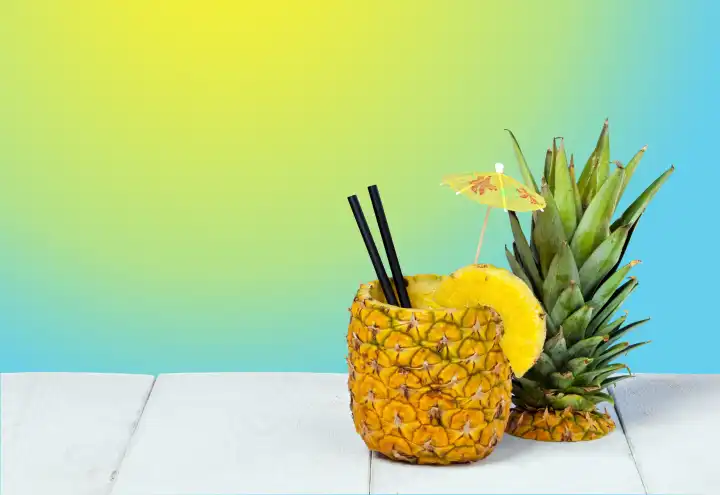 Pineapple juice served in the peel on background gradient