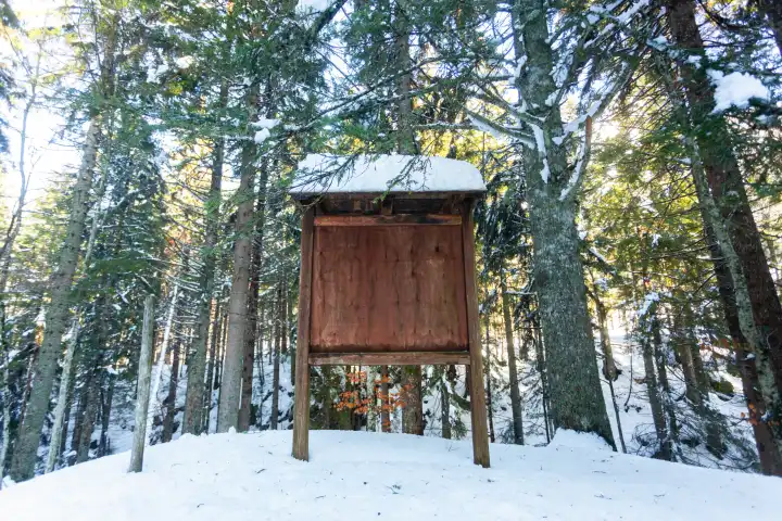 Große leere Holzplakatwand in winterlicher Berglandschaft.