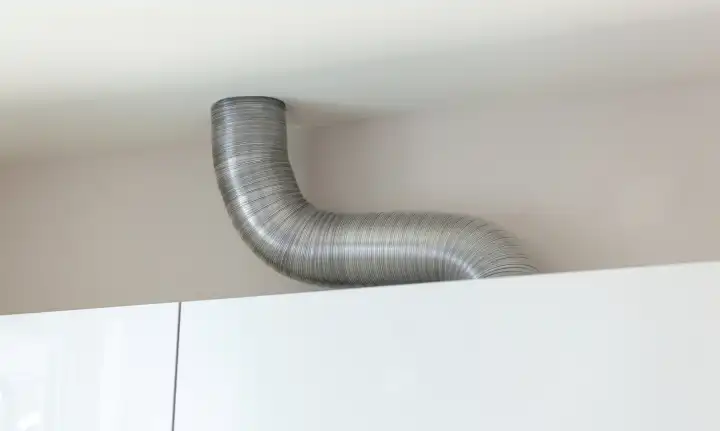 Expandable aluminium corrugated ventilation pipe in kitchen connecting a cooker hood and a ventilation air shaft.