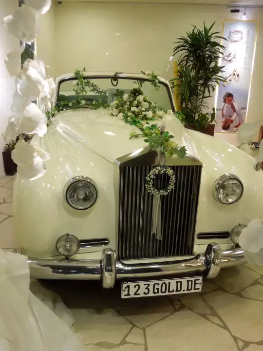 Eine weiße Hochzeitskutsche Rolls-Royce mit Hochzeitsschmuck