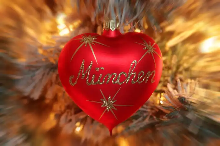 Christbaumkugel in Herzform mit Aufschrift München an einem beleuchteten Weihnachtsbaum