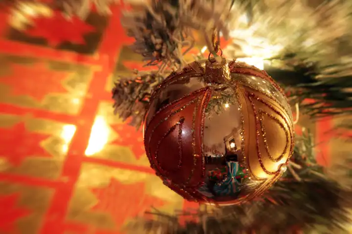 Heiligabend beleuchteter Weihnachtsbaum mit Christbaumkugel und einem Weihnachtsgeschenk vor der Bescherung, Deutschland
