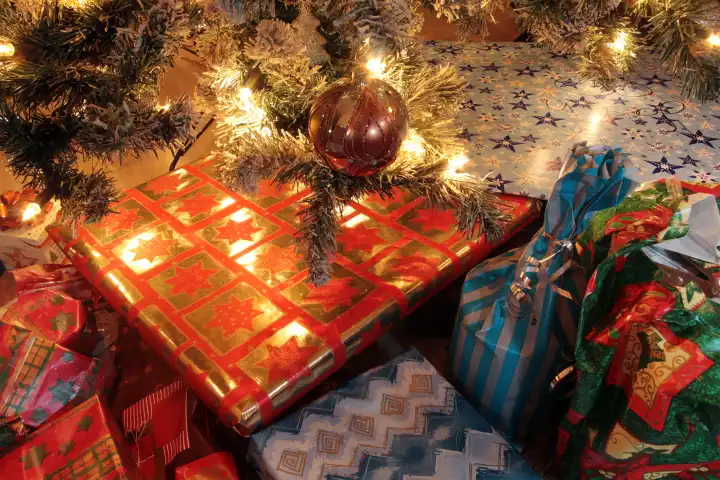Heiligabend beleuchteter Weihnachtsbaum mit Christbaumkugel und Weihnachtsgeschenken vor der Bescherung, Deutschland