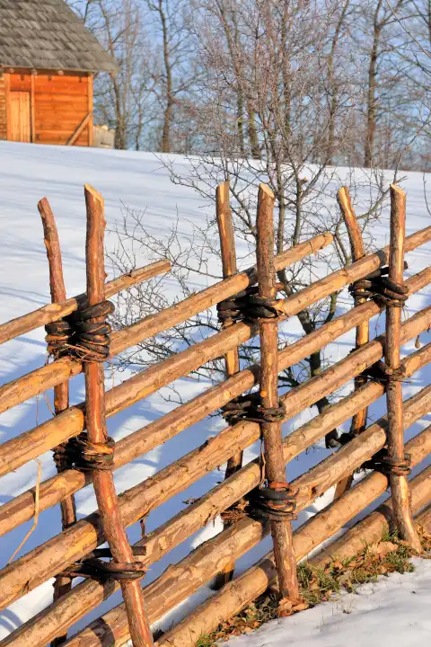 Wooden fence on a snow-covered pasture in winter
