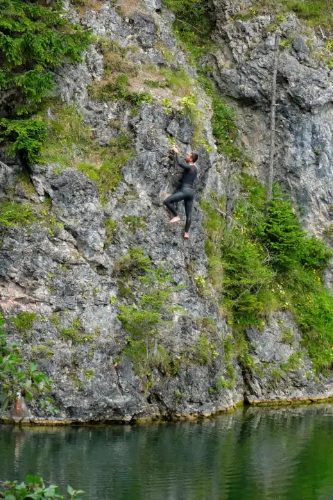 Mariazell, Austria - June 20, 2015 Climber on rock wall over lake