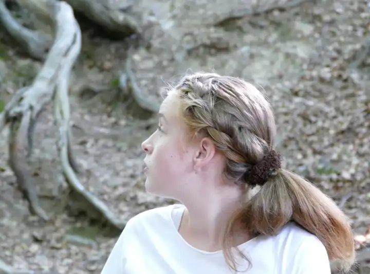 Girl with braided hair looking to the side and looks at a gigantic root system