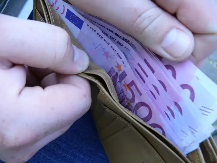 Money bag filled with 500 euro notes, counting the money
