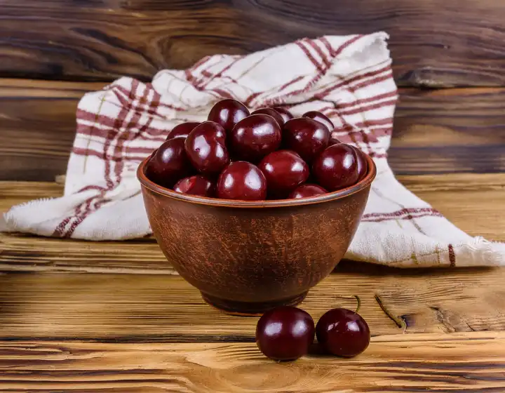 AI generated. Sweet ripe cherries in a small bowl on a wooden table