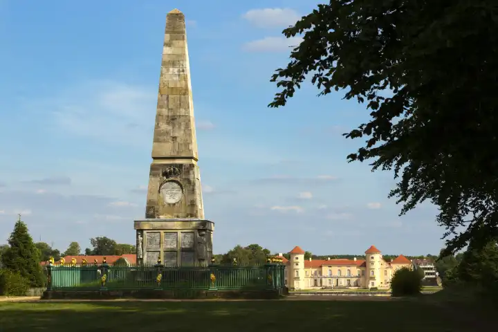 Obelisk in Reinsberg castle park with castle in the background.