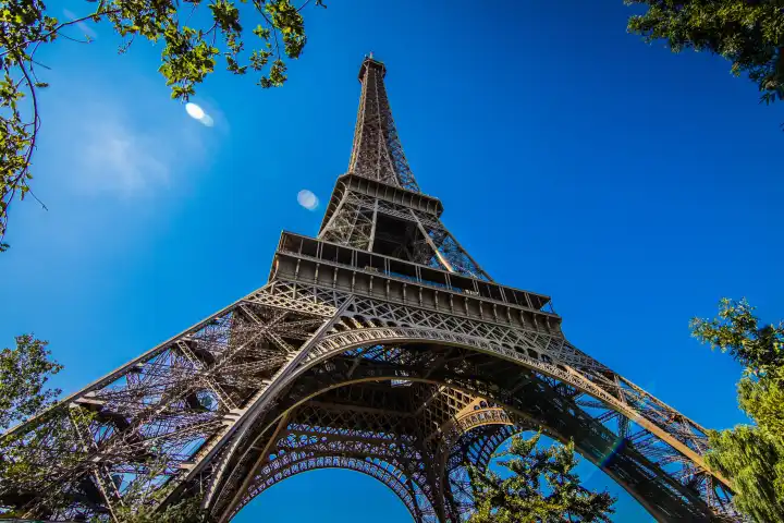 Wide angle view of the Eiffel Tower in Paris in front of a blue and cloudless sky