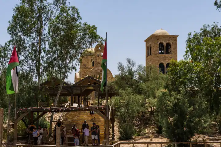 Taufstelle des Johannes am Jordan. Blick über den Jordan zum jordanischen Zugangspunkt zum Fluß. Jordanische Pilger stehen unter der jordanischen Flagge am Ufer des biblischen Flusses.