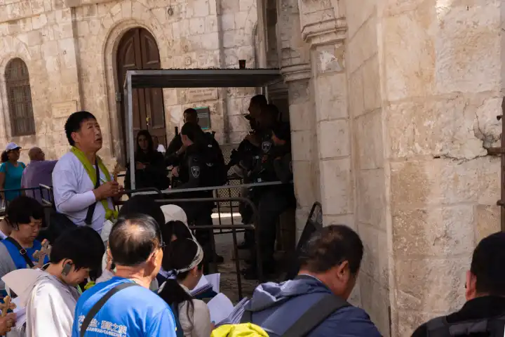 Pilger knien auf der Via Dolorosa an einer Station des Kreuzwegs Jesu in Jerusalem zum Gebet nieder. Im Hintergrund ein Checkpoint der israelischen Polizei und des Militärs in Ost-Jerusalem.