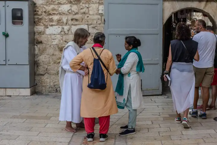 Jesus spricht in Jerusalem vor der Grabeskirche mit zwei Pilgerinnen. Jesus-Darsteller in der Altstadt von Jerusalem.