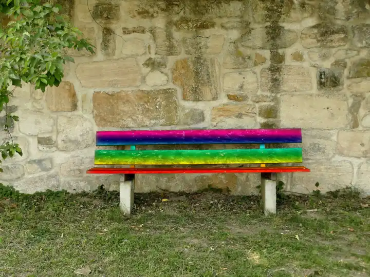 Parkbank an einer alten antiken Klostermauer mit LGBTQ-Farben