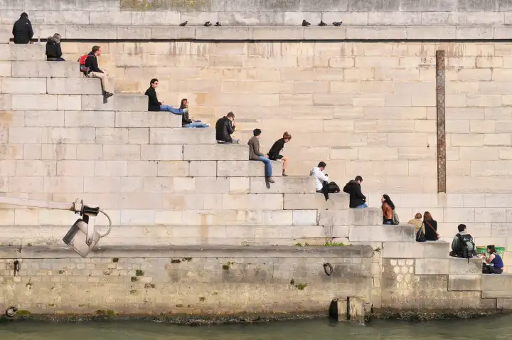 People relaxing on steps by the river Seine in Paris, France
