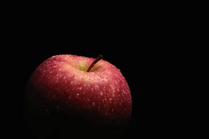 Apfel mit Wassertropfen schwach beleuchtet