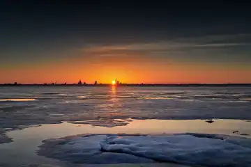 Silhouette of hanseatic city Stralsund with ice in foreground seen from Altefaehr in winter