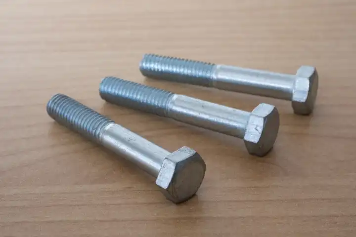 Hexagon head screws with shank on wooden background, steel screw, machine screw, wrench screw