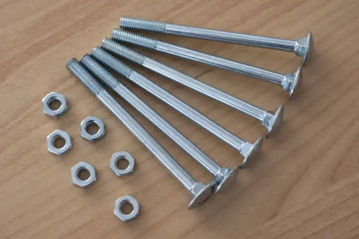 Truss-head bolts and hexagon nuts on wooden background, wrench bolts