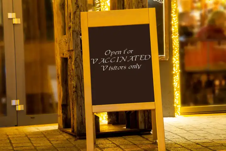 Street sign in front of a restaurant with the inscription Open for Vaccinated Visitors only Symbolic image, Composing