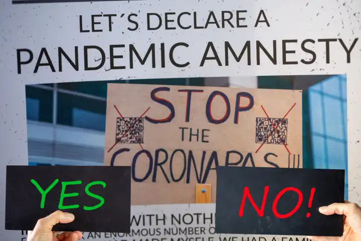 Symbolbild Pandemic Amnesty: Ausschnitt einer symbolischen Zeitung, davor werden Schilder mit der Aufschrift YES und NO gehalten. In den USA und vielen weiteren Ländern hat eine Debatte zur Aufarbeitung der Coronamaßnahmen begonnen