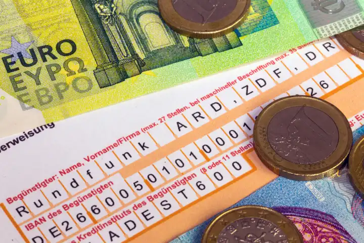 Symbolbild Rundfunkbeitrag: Nahaufnahme von einem Überweisungsträger, Eurobanknoten und Euromünzen