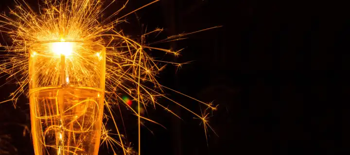 New year greetings: champagne glass with burning sparklers and free space for text
