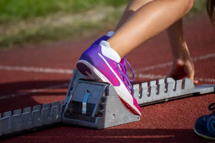 Young track and field athlete with spikes from Puma on the starting block before a sprint