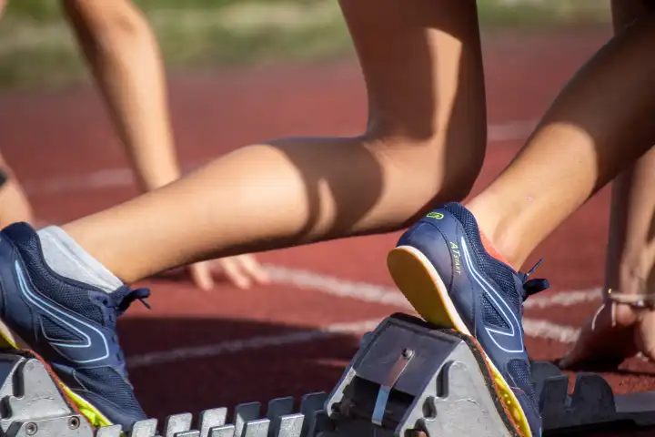 Young track and field athlete with spikes from Kalenji on the starting block before a sprint