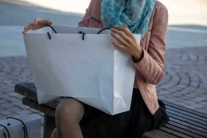 Junge Frau mit weißen Tragetaschen beim Einkaufen in der Stadt (model released)